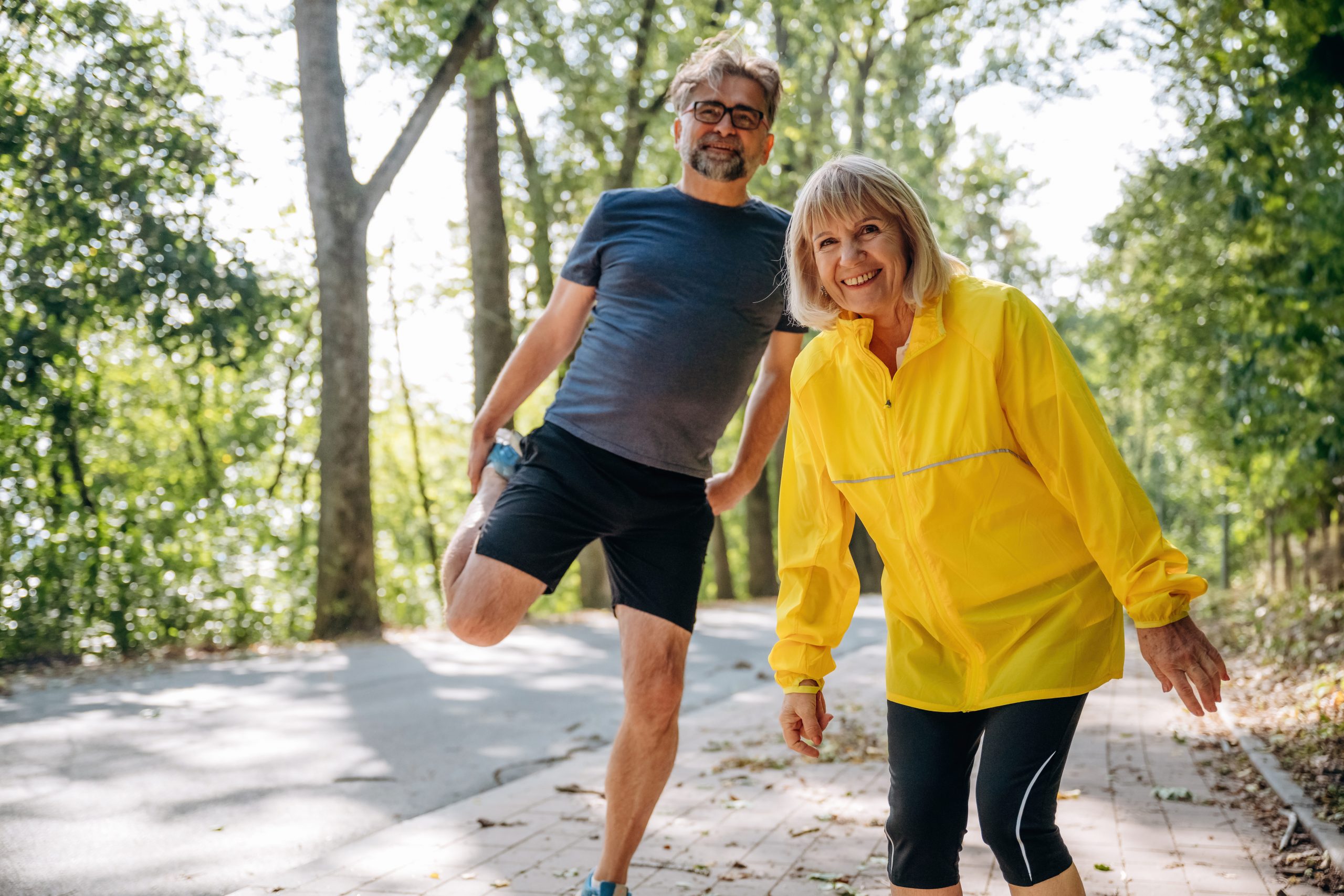 doing warm up exercises senior couple together outdoors nature scaled